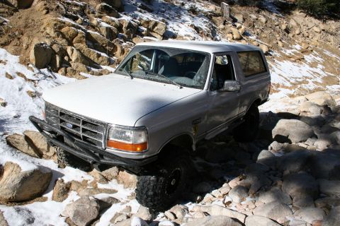 1996 Ford Bronco - White 1996 Ford Bronco tackling a challenging off-road course with snow on the ground.