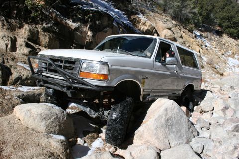 1996 Ford Bronco - This 1996 Ford Bronco is shown tackling a challenging off-road path with large rocks and patches of snow.