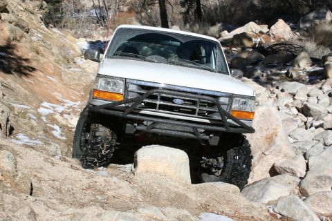 1996 Ford Bronco - A white Ford Bronco is shown off-roading on a rocky trail.