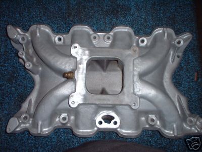 1972 Ford Ranchero - This aluminum intake manifold features a square opening for carburetor mounting and is shown against a blue carpeted surface.