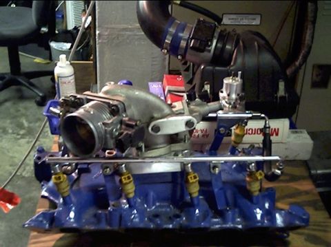1972 Ford Ranchero - Engine intake manifold assembly with fuel injectors and throttle body on a wooden surface.
