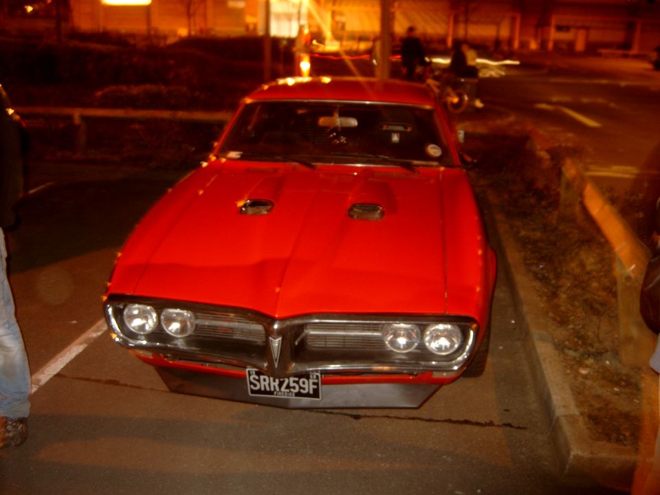 Red classic muscle coupe with hood scoops at night