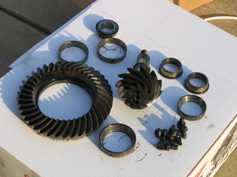 1989 Ford Bronco - A collection of automotive differential parts, including a ring gear and pinion, are displayed on a white surface.