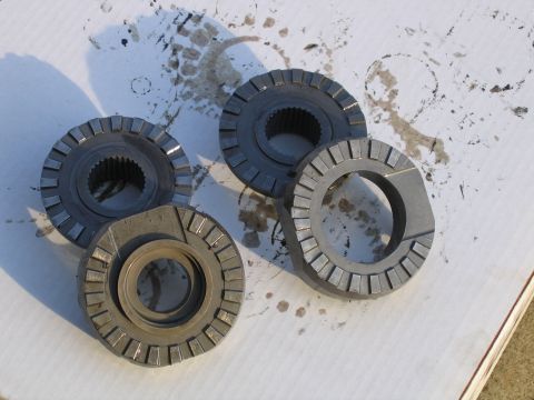 1989 Ford Bronco - Four differential gears are laid out on a white surface, showing signs of oil and wear.