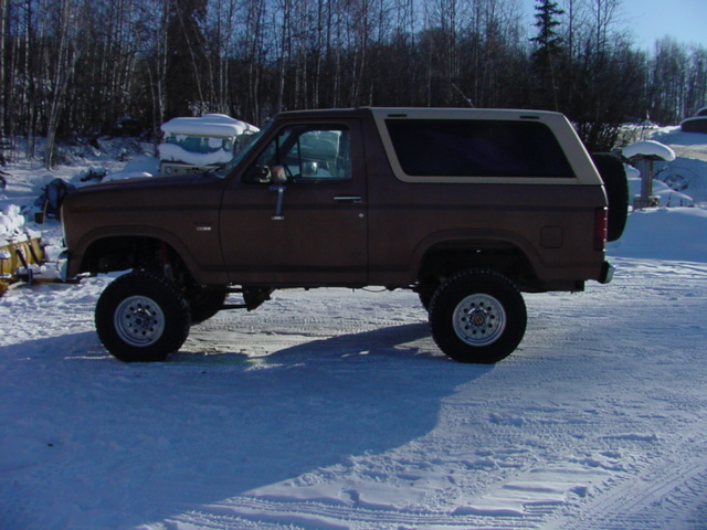 Brown Ford Bronco with a white top parked in the snow