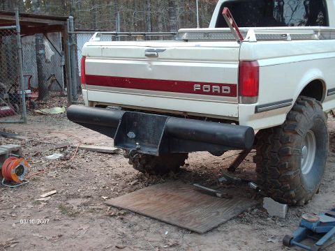 1990 Ford F-150 - Rear view of a white Ford pickup truck, likely a 1990 F-150, a custom bumper and off-road tires.