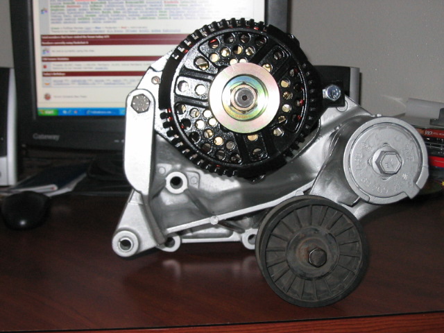 Alternator with black pulley wheel and silver mounting bracket on a wooden desk