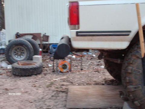 1990 Ford F-150 - Rear view of a white 1990 Ford F-150 pickup truck, showing the quarter panel and an aftermarket exhaust modification.