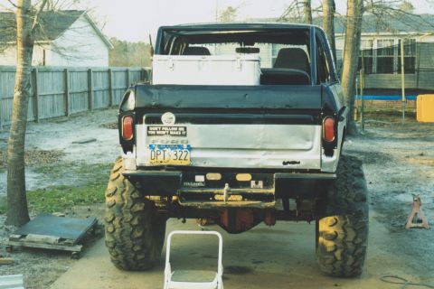 1978 Ford Bronco - Rear view of a topless lifted full-size Ford Bronco on huge mud tires, with a black-over-white tailgate carrying an Alaska plate reading DP…