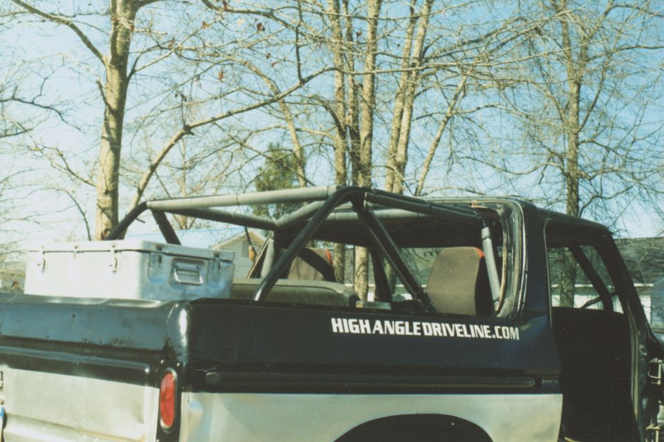 Black roll cage over the bed of a black and silver pickup truck with a metal toolbox