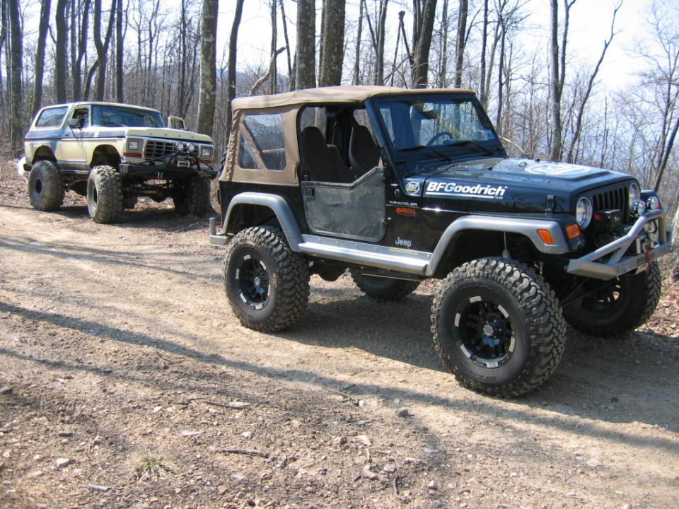 Jeep Wrangler and Ford Bronco on a dirt road in the woods