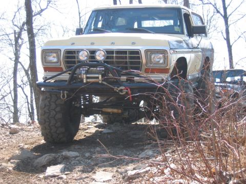 1992 Ford Mustang - A tan Ford Bronco is parked on a rocky incline, modified for off-road use with a winch and brush guard.