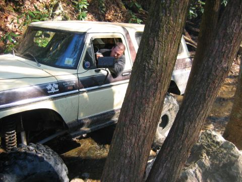 1992 Ford Mustang - Ford Bronco off-roading through a stream with a driver behind the wheel.