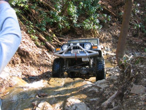1992 Ford Mustang - A Jeep Wrangler TJ navigates a rocky stream bed on an off-road trail.