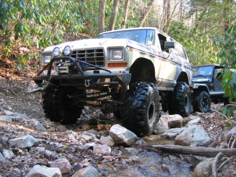 1992 Ford Mustang - A heavily modified 1978-1979 Ford Bronco navigates a rocky stream bed, followed by a Jeep.