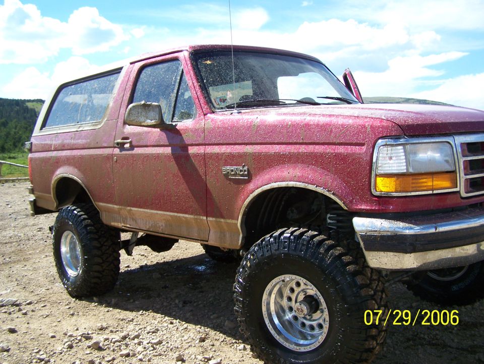 Red lifted 1995 Ford Bronco with aftermarket wheels and tires