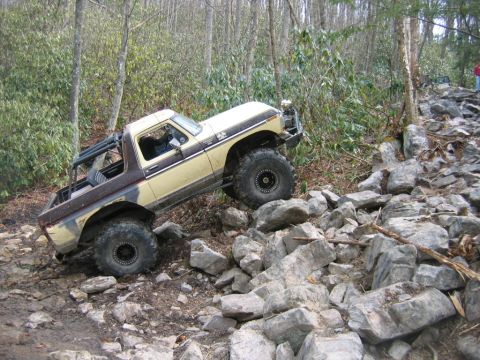 1992 Ford Mustang - An off-road vehicle navigates a rocky, wooded path, demonstrating its climbing capabilities.