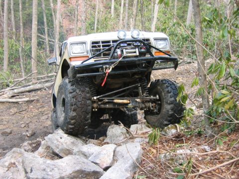 1992 Ford Mustang - This heavily modified truck navigates a challenging rocky trail in a wooded area.