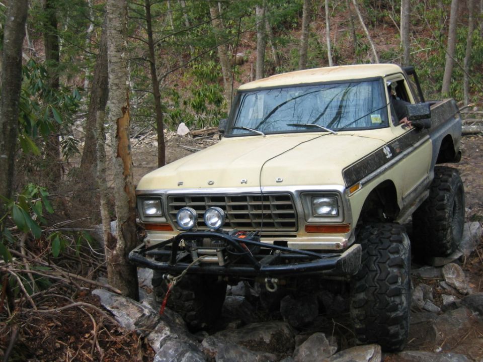 Tan and brown pickup truck with off-road tires and winch on rocky terrain