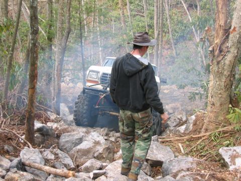 1992 Ford Mustang - Off-road vehicle navigating a challenging rocky trail in a wooded environment.