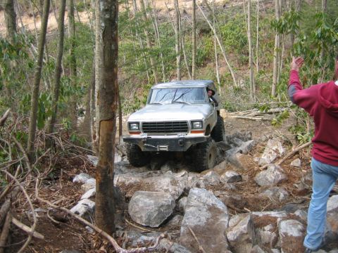 1992 Ford Mustang - Ford Bronco tackling a challenging off-road course with large rocks and steep inclines.