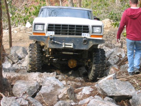 1992 Ford Mustang - A white off-road truck is shown from the front, with its large tires on a rocky path.