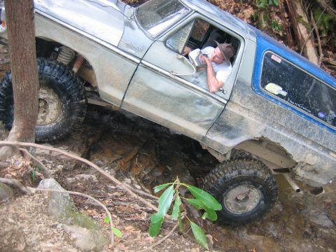 1992 Ford Mustang - A man in a hat drives a lifted Ford Bronco through a challenging off-road course.