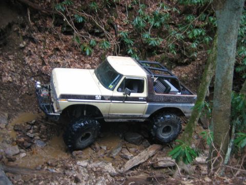 1992 Ford Mustang - This modified Ford Bronco is navigating a challenging muddy trail with large off-road tires.