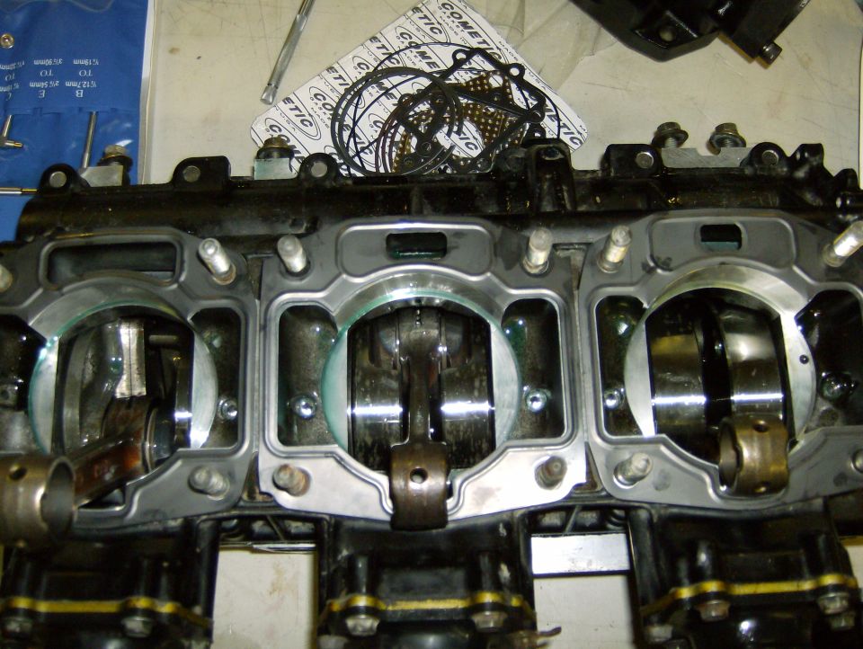 Engine block with pistons and crankshaft visible, gasket set in background