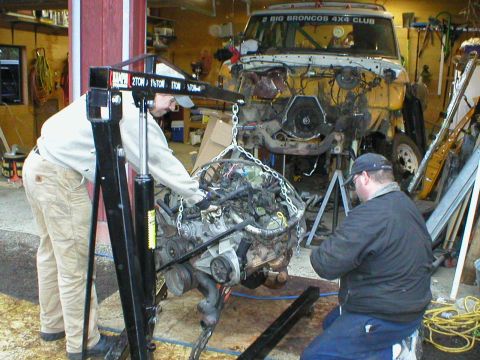 1978 Ford Bronco - Mechanics use an engine hoist to remove the powerplant from a disassembled Ford Bronco.