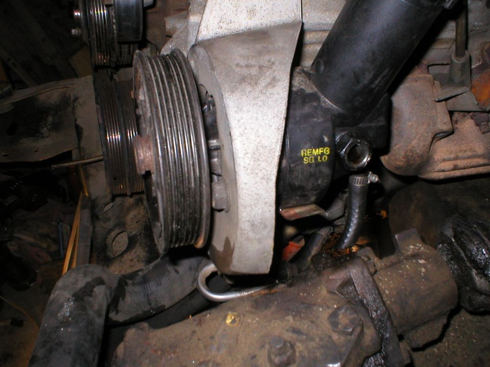 Reman power steering pump with serpentine pulley in engine bay, marked REMFG SO LO.