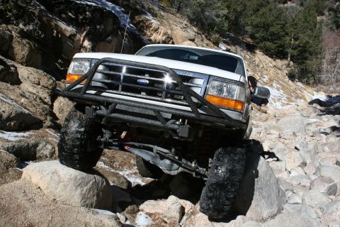 1996 Ford Bronco - This 1996 Ford Bronco navigates a rocky, off-road trail with snow patches visible.