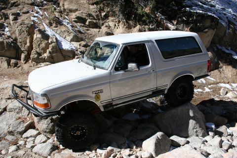 1996 Ford Bronco - This 1996 Ford Bronco is shown tackling a challenging off-road course with steep, rocky inclines and scattered snow.