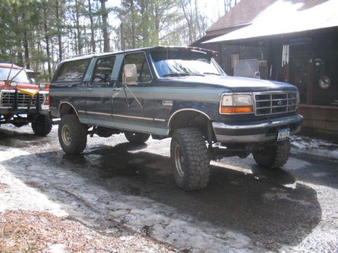 1979 Ford Bronco - This lifted SUV, likely a Ford F-Series based conversion, is parked in front of a wooden building.