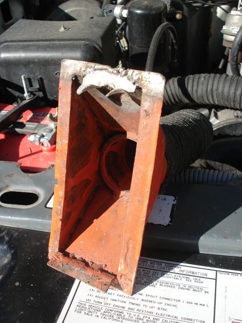 1986 Ford Bronco - Close-up of a rusted metal bracket in an engine bay, with some text visible on a sticker.
