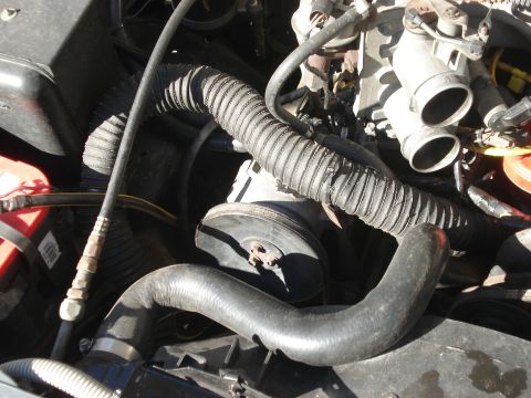 1986 Ford Bronco - Close-up view of engine components including hoses and a pulley system.