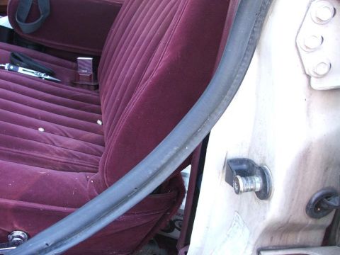 1991 Ford Crown Victoria LTD - Close-up of a car's interior door frame and seat, with a tool visible on the seat.