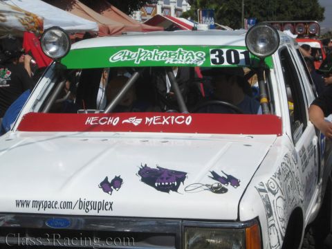 1990 Ford Bronco - front of a white Ford off-road race truck shows a 'Chupakabras 301' light bar, 'Hecho en Mexico' banner and purple skull hood decals.