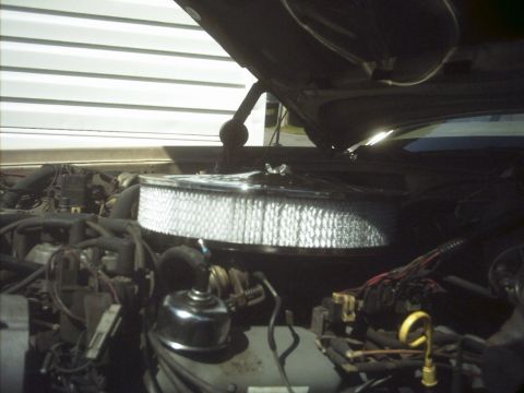 1985 Ford Crown Victoria LTD - Close-up of a car's engine bay, focusing on the air filter assembly and wiring. The year is not discernible.