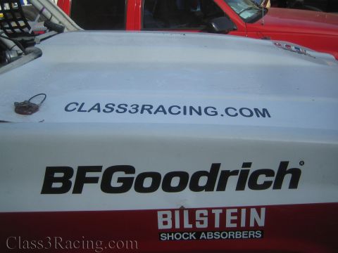 1990 Ford Bronco - white off-road truck hood lettered with BFGoodrich, Bilstein and Class3Racing.com sits next to a red vehicle.