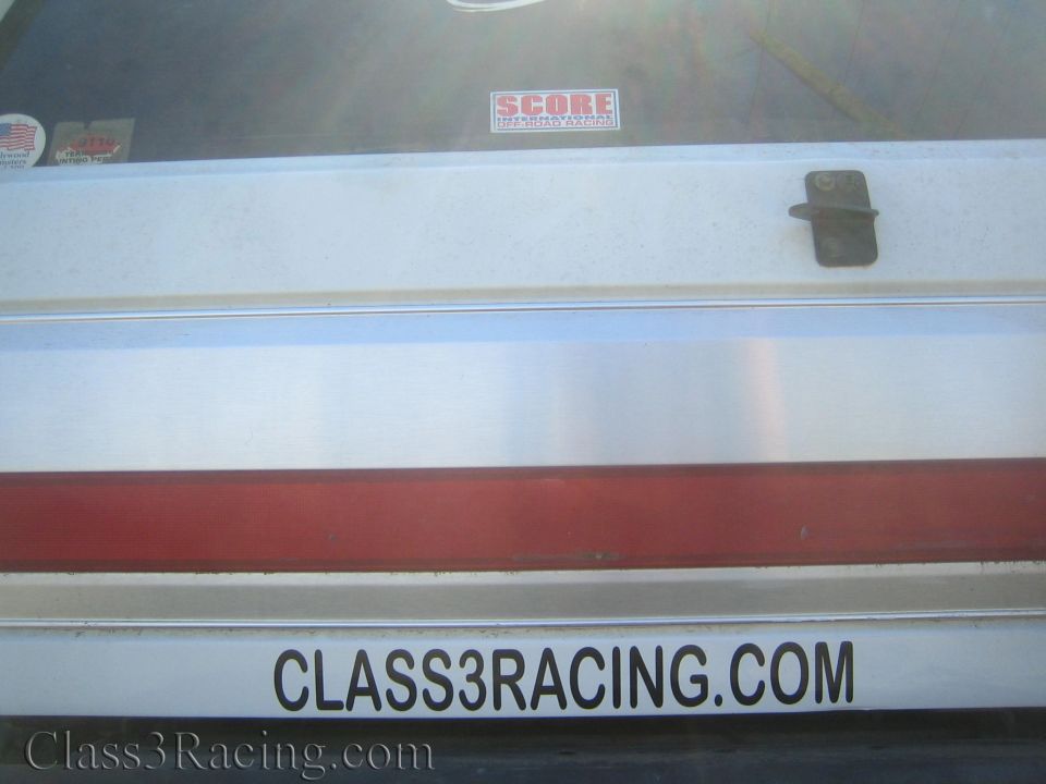 Rear panel of white vehicle with red stripe, SCORE sticker and Class3Racing.com decal