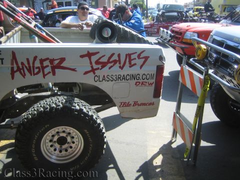 1990 Ford Bronco - white truck bed hand-lettered 'ANGER ISSUES' over Class3Racing.com and Elite Broncos decals, with a man leaning out the back.