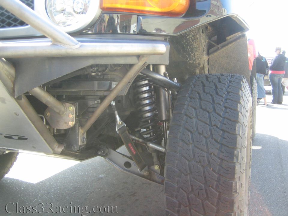 Front coilover shock, tube bumper and oversized tire on an off-road race vehicle