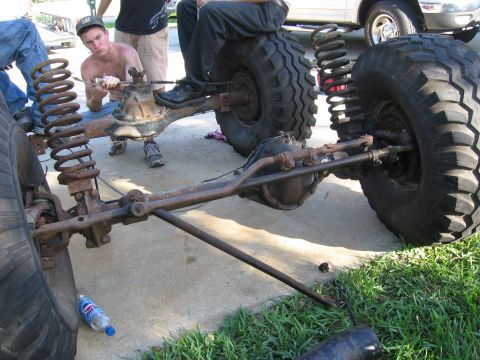 1974 Ford F-100 - Front axle and suspension components are visible as people work on the vehicle.