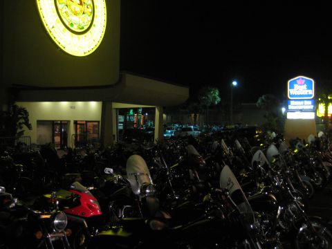 1986 Ford Bronco - A large group of motorcycles are parked in a lot outside a hotel at night, with a Best Western sign illuminated.
