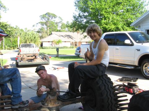 1974 Ford F-100 - People are gathered around vehicle parts in a driveway with a white Ford F-150 parked nearby.