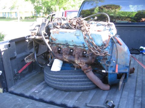 1974 Ford F-100 - A V8 engine, likely removed from a vehicle, is being transported in the bed of a pickup truck.