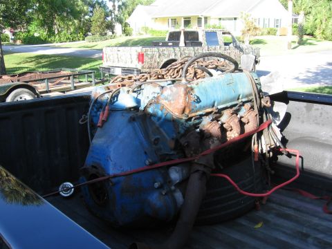 1974 Ford F-100 - Engine block and components loaded into the bed of a pickup truck, with a trailer in the background.