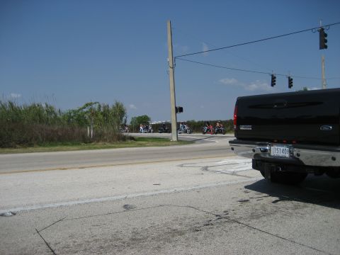 1986 Ford Bronco - A group of motorcycles rides down a road on a clear day, with a black pickup truck in the foreground.