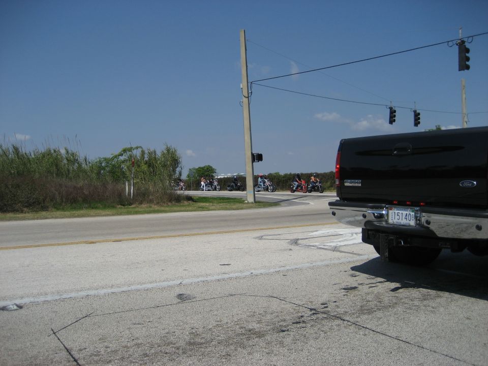 Black pickup truck rear view, motorcycles riding in distance on a sunny day